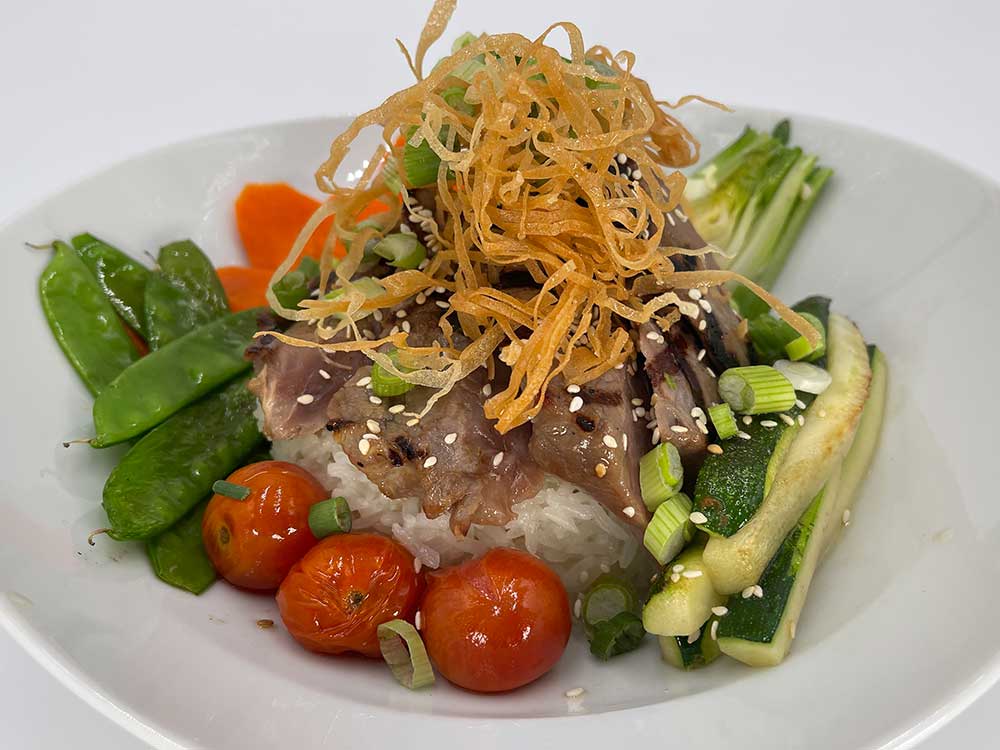 Teriyaki beef bowl surrounded by vegetables